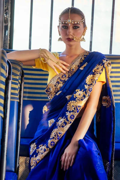 Портрет індійської прекрасної кавказької жінки в традиційному блакитному платті. Індуїстська модель з золотими kundan ювелірні вироби набір Бінді сережки і ніс кільце пірсинг нату мода Фотосесія в автобусі — стокове фото