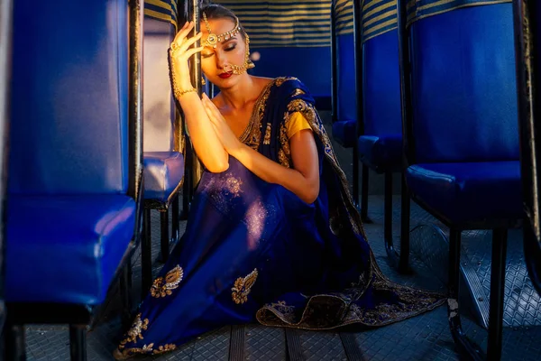 Портрет індійської прекрасної кавказької жінки в традиційному блакитному платті. Індуїстська модель з золотими kundan ювелірні вироби набір Бінді сережки і ніс кільце пірсинг нату мода Фотосесія в автобусі — стокове фото