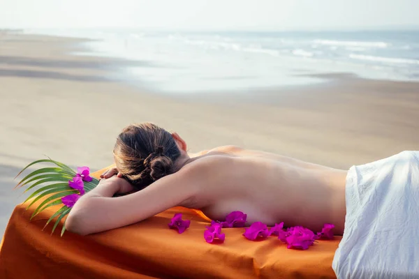 Massagem relaxante ayurvédica, mulher de saúde no salão de spa recebendo massagem na praia de férias.Menina bonita desfrutando resort spa dia, deitado na mesa de tratamento procedure.male mestre terapeuta pescoço — Fotografia de Stock