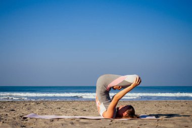 Beyaz kadın deniz kıyısında sabah yaz plajda yoga pratik