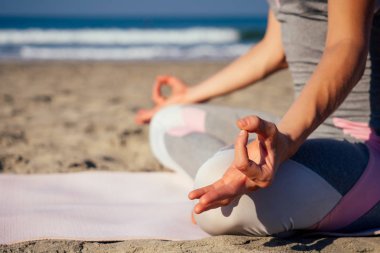 Beyaz kadın deniz kıyısında sabah yaz plajda yoga pratik