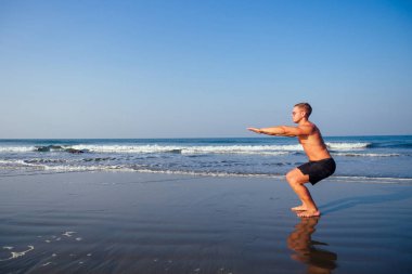 Adam gün doğumunda sahilde ısınmak