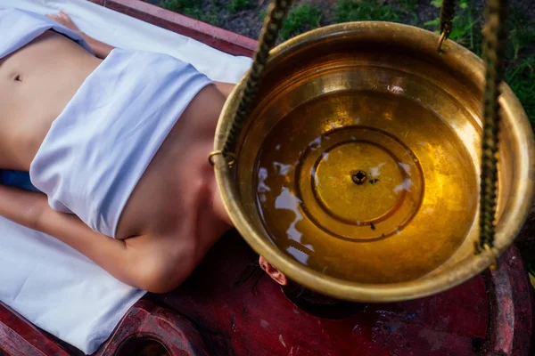 Ayurveda masaje alternativa de curación therapy.beautiful mujer caucásica conseguir tratamiento shirodhara acostado en una mesa de madera en el salón de la India — Foto de Stock