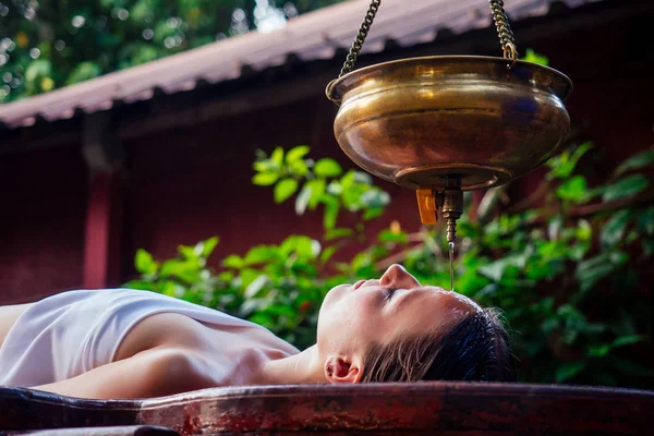 ayurveda masaj alternatif şifa terapisi.güzel kafkas kadın Hindistan salonda ahşap bir masa üzerinde yatan shirodhara tedavi alıyorum