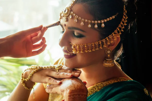 Retrato indio hermosa hembra en oro rica joyería tradición cara saree primer plano maquillaje profesional con bindi en la cabeza, con bindis maang tikka, nath, nariz Pin.morning de la novia visagiste —  Fotos de Stock