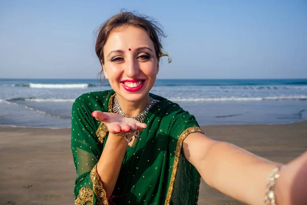 Modelo feminino brincos colar em férias no paraíso praia tropical por mar oceânico. mulher hindu com jóias kundan traje tradicional da Índia sari.girl tirar fotos-se no telefone da câmera indiano — Fotografia de Stock