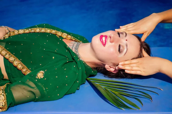Genç güzel hintli kadın bindi üçüncü göz yeşil şık sari sahip yağ Ayurveda spa tedavisi. Yüzme yaz havuzu tropikal tatil rahatlayın tay masajı
