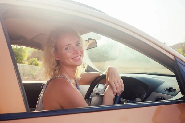 Jovem mulher sentada no carro e falando no pôr do sol telefone na orla . — Fotografia de Stock