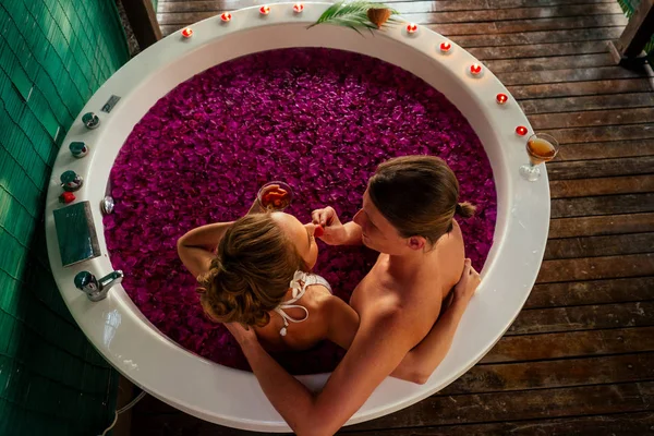 Novia de la boda night.beautiful y novio guapo relajarse en baño flores tropicales en el hotel de lujo resort.couple en el amor clink gafas eco bali spa.candles, fecha romántica Día de San Valentín 14 de febrero — Foto de Stock