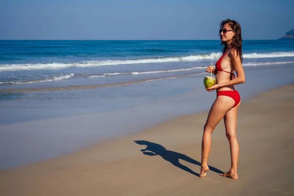 Schöne sexy junge Frau posiert hübsch mit Kokosnuss und Schlauch am tropischen Strand, Sommer-Detox-Blick von hinten — Stockfoto