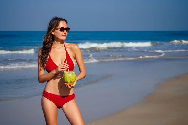 Schöne sexy junge Frau posiert hübsch mit Kokosnuss und Schlauch am tropischen Strand, Sommer Detox — Stockfoto