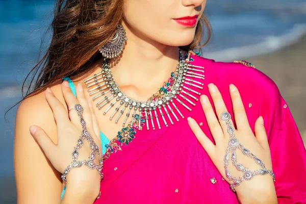 Female model earrings and necklace in vacation on paradise tropical beach by ocean sea. hindu woman with kundan jewelry traditional India costume sari.girl near the rocks shores of Indian Ocean bay — Stock Photo, Image