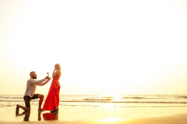 로맨틱 2 월 14 발렌타인 데이 여름 휴가, 관계 데이트.사랑 부부는 해변에서 자신의 손에 장미와 긴 드레스와 흰색 셔츠와 금발 의 꽃꽃 꽃 남자와 함께 — 스톡 사진