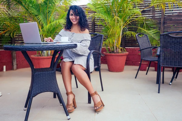 Женщина афро-американская предпринимательница работает на ноутбуке сидя в летнем тропическом кафе фрилансером серфинга — стоковое фото