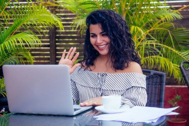Kahve fincanının yanında laptopuyla oturan koyu tenli genç iş kadını. Bağımsız çalışan Hintli kadın tropikal tatil köyünde yoga yapıyor.