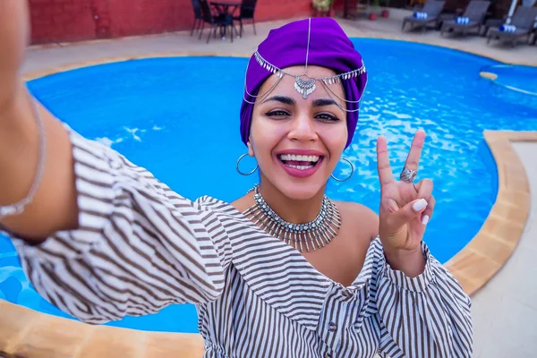 young africa woman photographing mobile camera blogger summer vacation holiday against the backdrop of the swimming pool.indian girl video link having fun in tropical resort