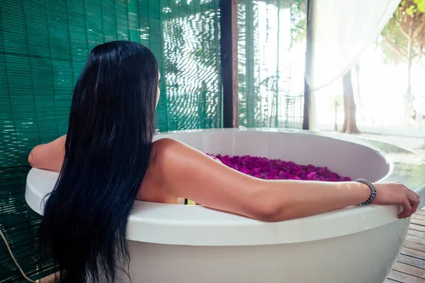 Mulher sexy morena relaxante no banho com flores tropicais ao ar livre no resort hotel de luxo. Cuidados de saúde da pele orgânicos. Menina bonita descansando em hotel spa massagem e meditation.womens Dia 8 de março — Fotografia de Stock