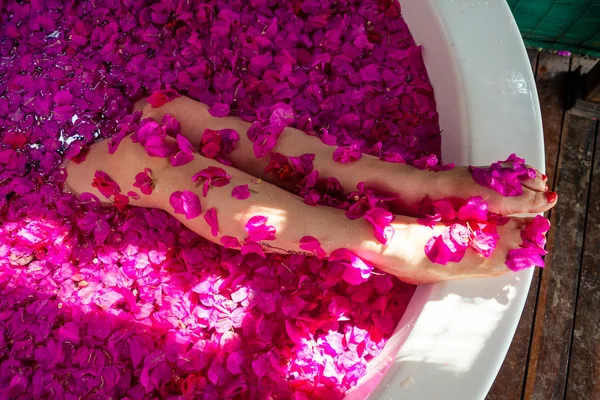 Cropped shot of barefoot woman with flowers, candles, colorful sea salt and bath for nails in beauty salon in hotel — Stock Photo, Image