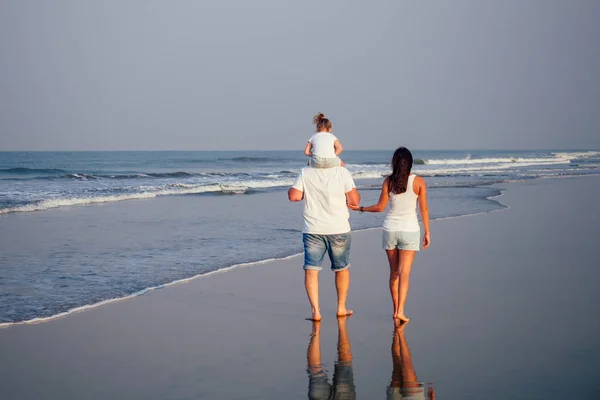 Szczęśliwa rodzina trzymanie rąk na plaży i oglądanie sunrice zachód słońca na Goa oceanu indyjskim — Zdjęcie stockowe