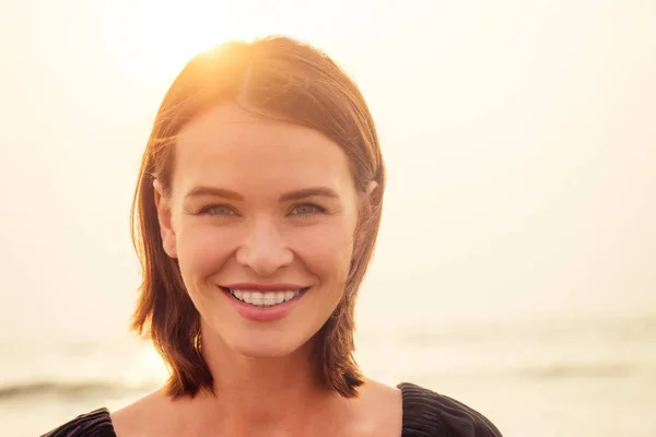 woman, 30-35 years old smiling toothy smile with braces on sea ocean beach background.spf and sunscreen