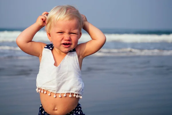 Adorable small sleepy girl at beach applying sunblock cream.one year old fair-haired baby child sweet big belly swollen summer holiday tropics allergy