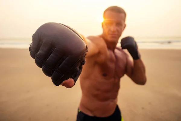 Sterke bokser man doen tijdens kickboksen oefening vechten met trainer bij zonsondergang. Close portret van knappe fitness mannelijk model bodybuilder woede, woede en een plons van negatieve emoties — Stockfoto