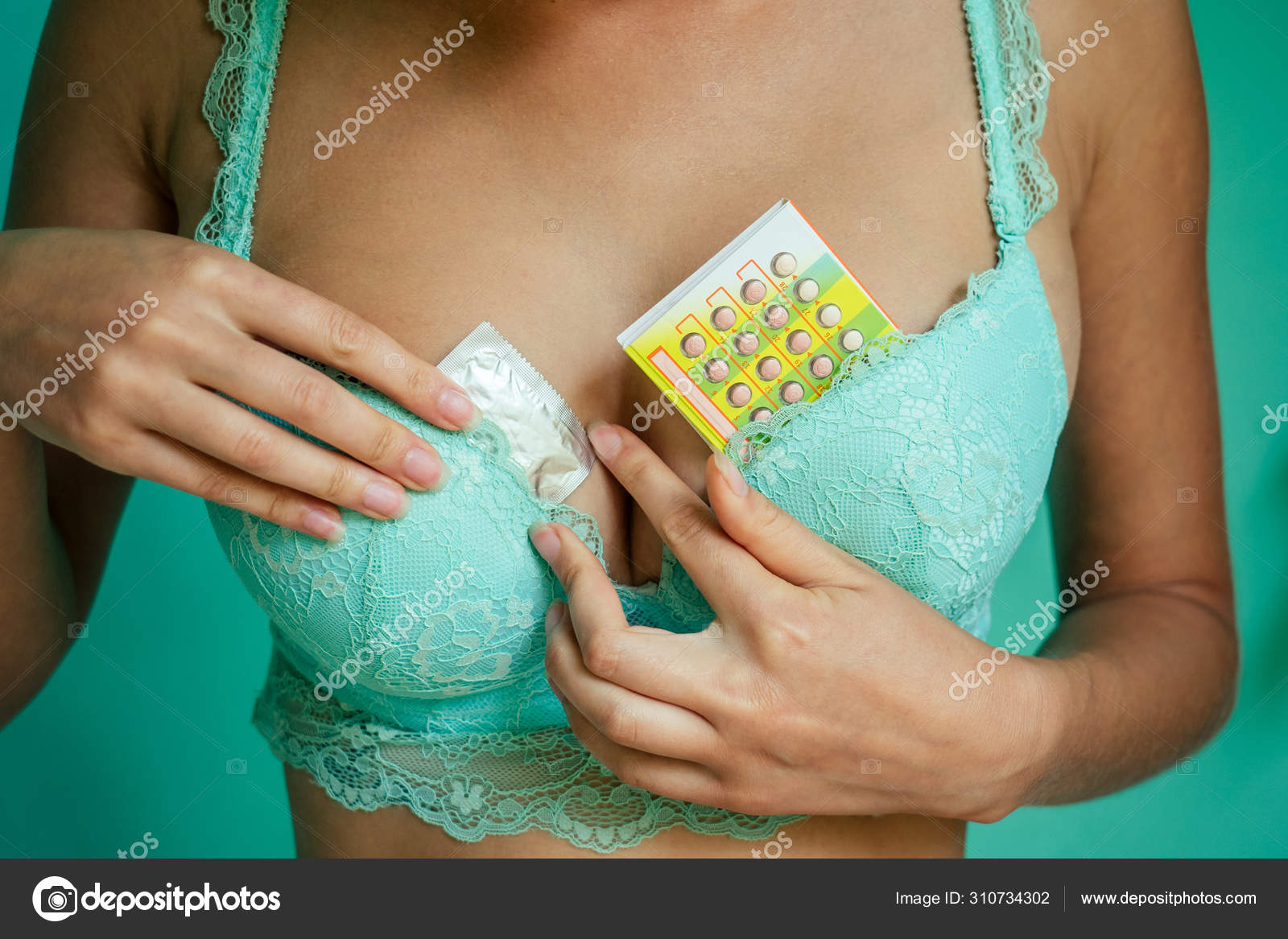 Молодая женщина в красивом нижнем белье держит контрацептивы в руках 
