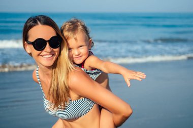 Anne kız sahilde dinlenirken eğleniyor.