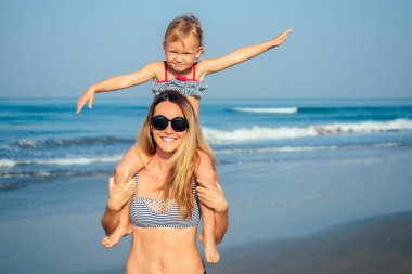 Anne kız sahilde dinlenirken eğleniyor.