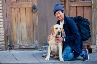 Sırt çantası ve sokakta köpeği olan Koreli hoş bir turist.