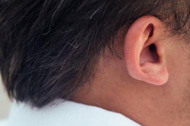 Mutlu ve neşeli, siyah saçlı bir adamın kulağı.