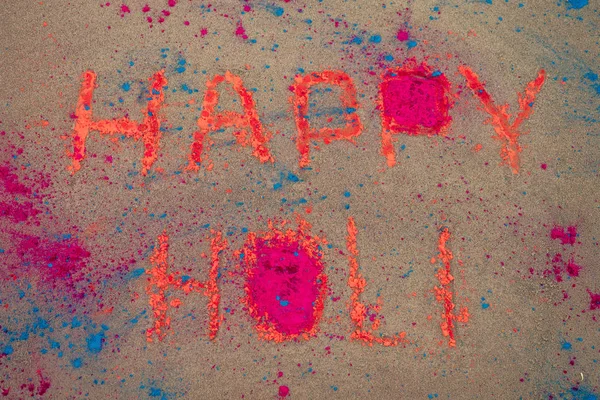 Happy Holi inscriptie op het zand blauw en oranje stof heilig — Stockfoto