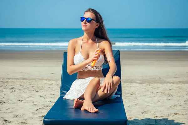 Bela e sexy jovem mulher está aplicando protetor solar no corpo no mar. Proteção contra raios ultravioleta e prevenção contra o câncer de pele em férias — Fotografia de Stock