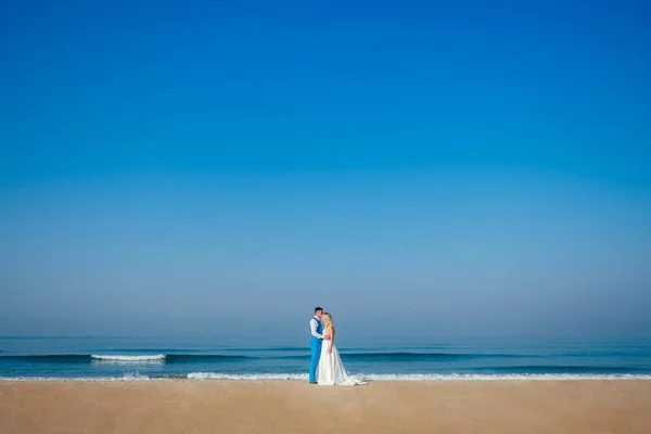 Noivo bonito em um terno chique e uma noiva bonita em um vestido de noiva na praia. conceito de uma cerimônia de casamento chique e rico na praia. espaço de cópia — Fotografia de Stock