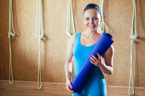 Портрет молодої і красивої жінки з тренувальним килимком для йоги. фіолетовий килимок в руках жінки. концепція концентрації і практики йоги — стокове фото