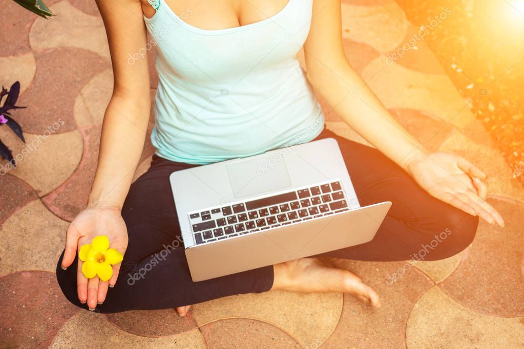 young woman freelancer meditating in lotus pose with laptop