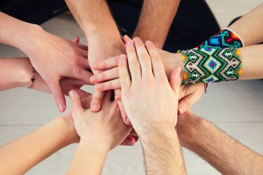 Stüdyoda yoga yapan mutlu bir grup insan. Yoga sınıfında meditasyon ve destek grupları. Grup meditasyonu ve takım çalışması kavramı. Eller yakın çekim. Destek Grubu