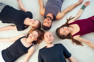 Stüdyoda yoga yapan kadın ve erkeklerden oluşan mutlu bir grup. Meditasyon grupları, iletişim yoga sınıfı. Grup meditasyonu ve takım çalışması kavramı. Koç ve öğrenciler daire oluşturun.