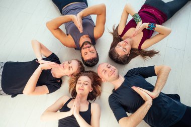 Stüdyoda yoga yapan kadın ve erkeklerden oluşan mutlu bir grup. Meditasyon grupları, iletişim yoga sınıfı. Grup meditasyonu ve takım çalışması kavramı. Koç ve öğrenciler daire oluşturun.