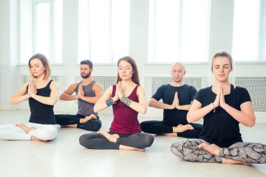 Stüdyoda yoga yapan kadın ve erkeklerden oluşan mutlu bir grup. Meditasyon grupları, iletişim yoga sınıfı. Grup meditasyonu ve takım çalışması kavramı. Koç ve öğrenciler daire oluşturun.