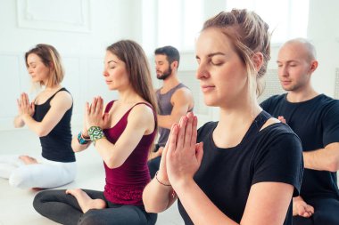 Stüdyoda yoga yapan kadın ve erkeklerden oluşan mutlu bir grup. Meditasyon ve iletişim yoga sınıfı grupları. Grup meditasyonu ve takım çalışması kavramı. Anti-stres kavramı