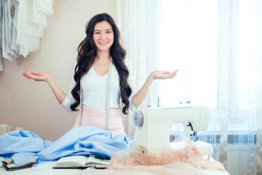 Uzun saçlı, gülümseyen güzel bir terzi kadın. Terzi bir kıyafet koleksiyonu yaratıyor. İlham perisinden esinlenmiş genç kadın tasarımcı kıyafetleri. ilham perisi, fikir ve ilham konsepti