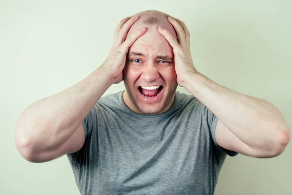 Un retrato de un hombre calvo es triste sobre un fondo gris. problema de la calvicie de patrón masculino. tristeza, molestia e ira —  Fotos de Stock