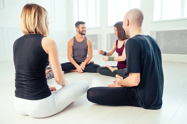 a happy group of people from men and women practicing yoga in the studio. groups of meditation , communication yoga class. the concept of group meditation and teamwork. coach and students in a circle