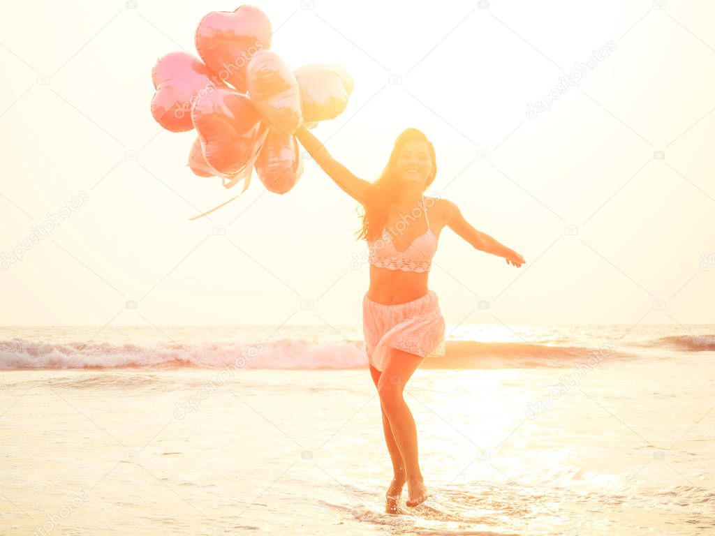 beautiful and young woman holding balloons in the beach. lightness and holiday concept