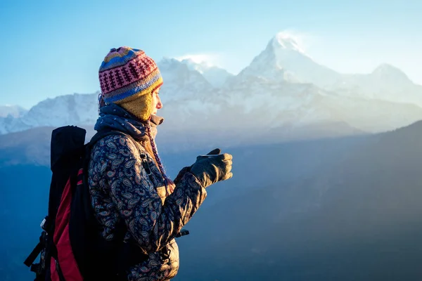 Uma mulher bonita e ativa segura um copo com uma bebida quente em suas mãos. o conceito de recreação ativa e turismo nas montanhas. trekking no Nepal Himalaia — Fotografia de Stock