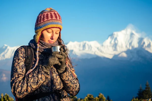 Una donna bella e attiva tiene in mano una tazza con una bevanda calda. il concetto di ricreazione attiva e turismo in montagna. trekking in Nepal Himalaya — Foto Stock