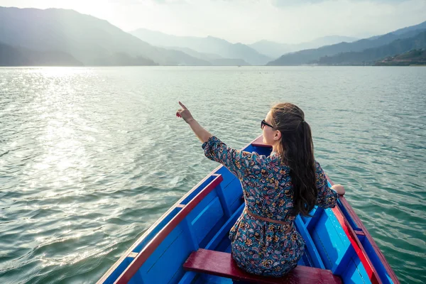Güzel ve genç bir kadın dağların arkasındaki gölde bir teknede. Doğadaki doğa aktiviteleri ve turizm kavramı. Nepal Himalayaları 'nda yürüyüş