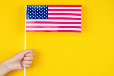 Sarı arka planda Amerikan bayrağı tutan bir kadın. Amerika 'nın Bağımsızlık Günü Konsepti 4 Temmuz