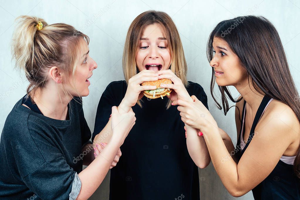 three friends persuade the girl not to eat a burger. concept of diet and female friendship